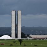 Vista externa do Congresso Nacional do Brasil, em Brasília, com suas cúpulas e torres diante do céu claro.